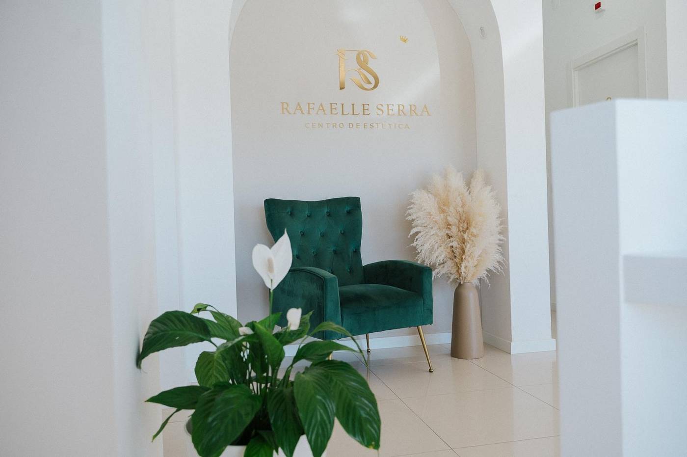 Receção do centro de estética Rafaelle Serra em Albufeira, com cadeirão de veludo verde e arco